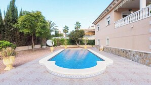 A swimming pool with a white border and a patterned tile floor, surrounded by greenery and a building with a balcony. - 2Bed Apartment - Sleeps 5 - Pool, Parking, Pets (BENFERRI)