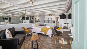 A compact living space with a bed, sofa, dining table, and chairs. A kitchen area is visible in the background. - Cozy Gulf View Studio in Panama City Beach, perfect for 3 guests. (Panama City Beach)
