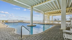 An indoor swimming pool with a clear view of the ocean, surrounded by lounge chairs and a covered area with a pergola. - Cozy Gulf View Studio in Panama City Beach, perfect for 3 guests. (Panama City Beach)