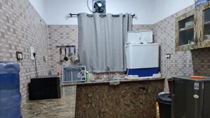 Een kleine keuken met een betegelde spatwand, een gootsteen, een ventilator en een koelkast.