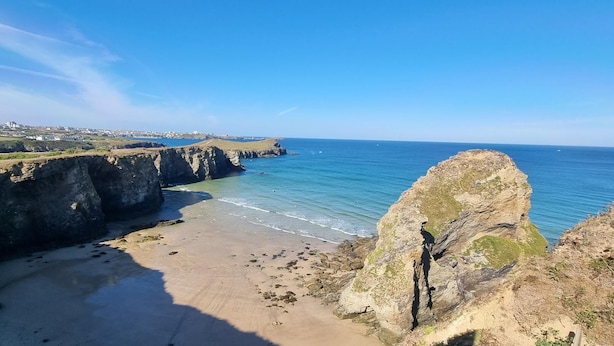 A coastal landscape with cliffs, a beach, and a view of a town in the distance. - 3 Bedroom Holiday Home in Newquay - Valley Views (Newquay)