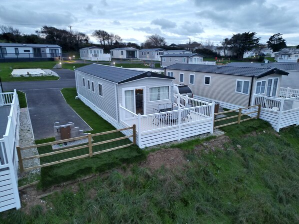 A row of mobile homes with attached porches and a fenced area.