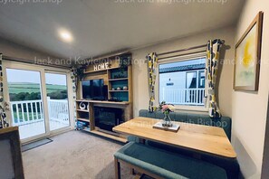 Relax by the fireplace in this inviting living room with a TV and comfortable seating area, offering a view of the outdoors.