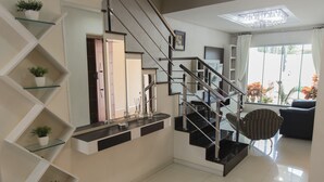 A modern staircase with glass railings and a black handrail, leading to a landing with a black countertop and potted plants. - Mansão Luxo Foz do Iguaçu - Click (Foz do Iguaçu)