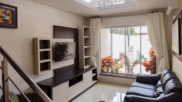 A modern living room with a sofa, TV, and built-in shelves. - Mansão Luxo Foz do Iguaçu - Click (Foz do Iguaçu)