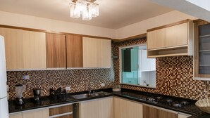 A modern kitchen with wooden cabinets, a black countertop, and a mosaic tile backsplash. - Mansão Luxo Foz do Iguaçu - Click (Foz do Iguaçu)