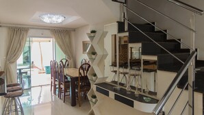 A modern interior with a staircase, dining area, and a view through a glass door. - Mansão Luxo Foz do Iguaçu - Click (Foz do Iguaçu)