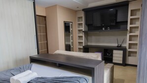 A modern hotel room with a bed, a desk, a TV, and built-in shelving. - Mansão Luxo Foz do Iguaçu - Click (Foz do Iguaçu)