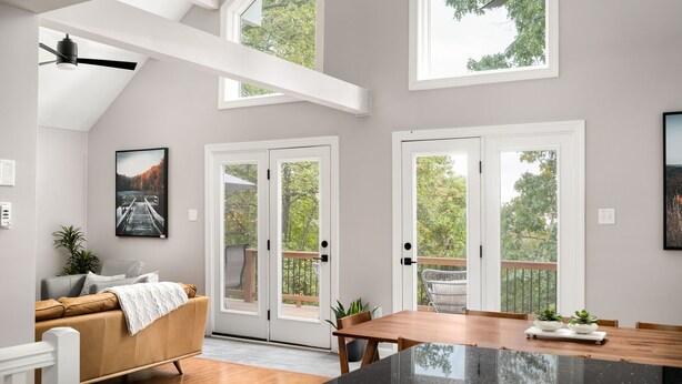 A modern kitchen with a black countertop, wooden dining table, and a view of the outdoors through large sliding glass doors. - Mountain cabin near national park & wineries (Linden)