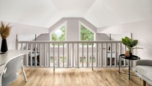 A modern loft bedroom with a high ceiling, wooden flooring, a white railing, and large windows offering a view of the outdoors. - Mountain cabin near national park & wineries (Linden)