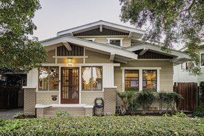 A two-story house with a front porch, a garage, and a well-maintained garden.