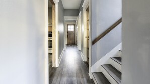 Ein schmaler Flur mit einer Holztreppe rechts und einem Schrank links.