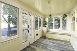 Relax in this serene sunroom with large windows, potted plants, and a cozy stone bench.