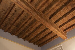 A room with a wooden ceiling structure, a door, and a light-colored wall.