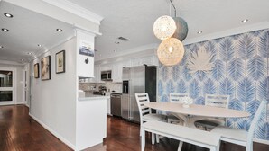 A modern kitchen with white cabinetry, stainless steel appliances, and a dining area with a white table and chairs. - Luxury Lakefront - Game Room - 7 beds - Hot tub - Kayaks - Dock (Montgomery)