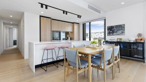 Una cocina moderna con una isla central, taburetes de bar y una mesa de comedor con sillas.
