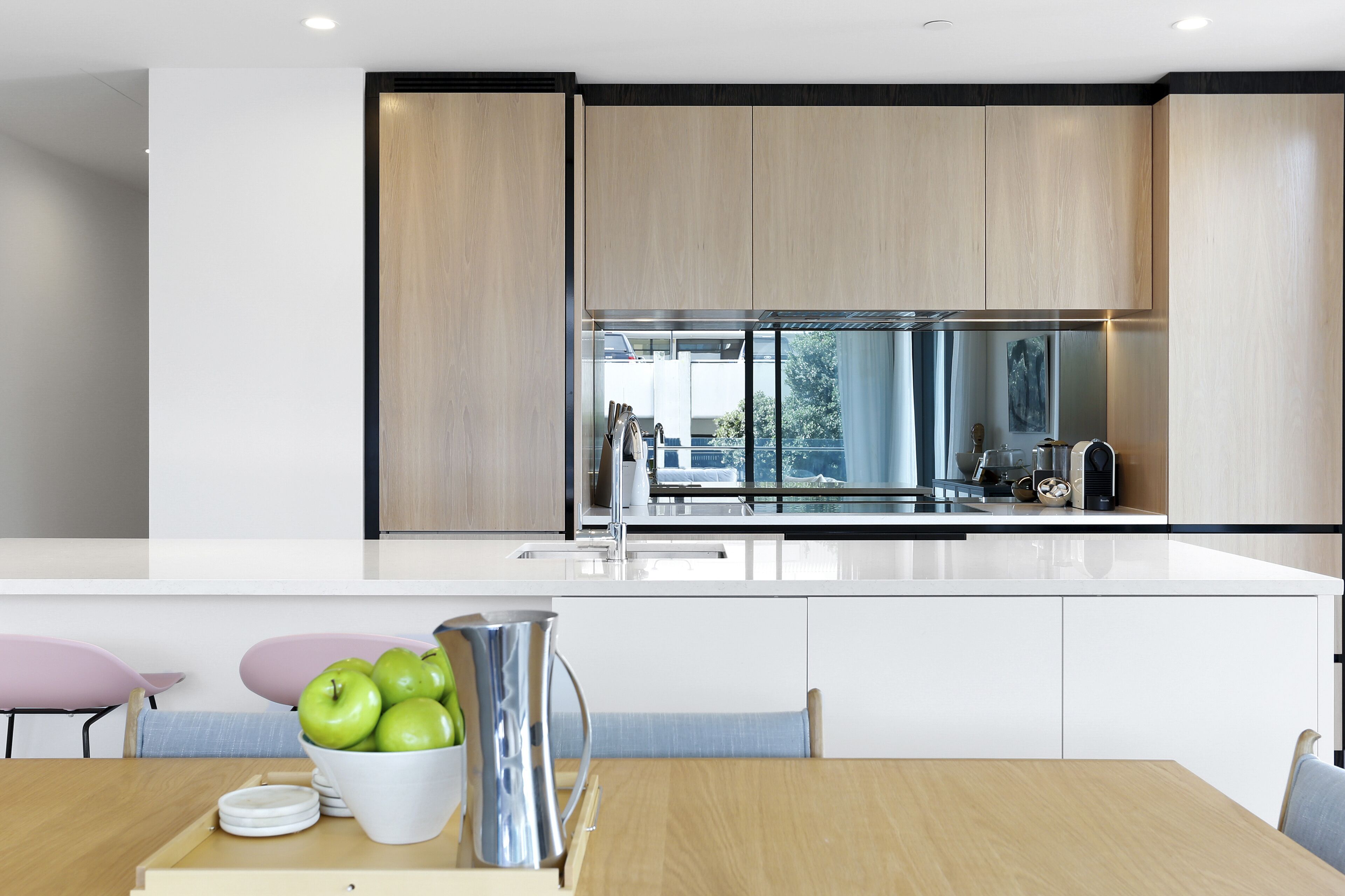 A modern kitchen with a large island, white cabinetry, and a view of the outdoors.