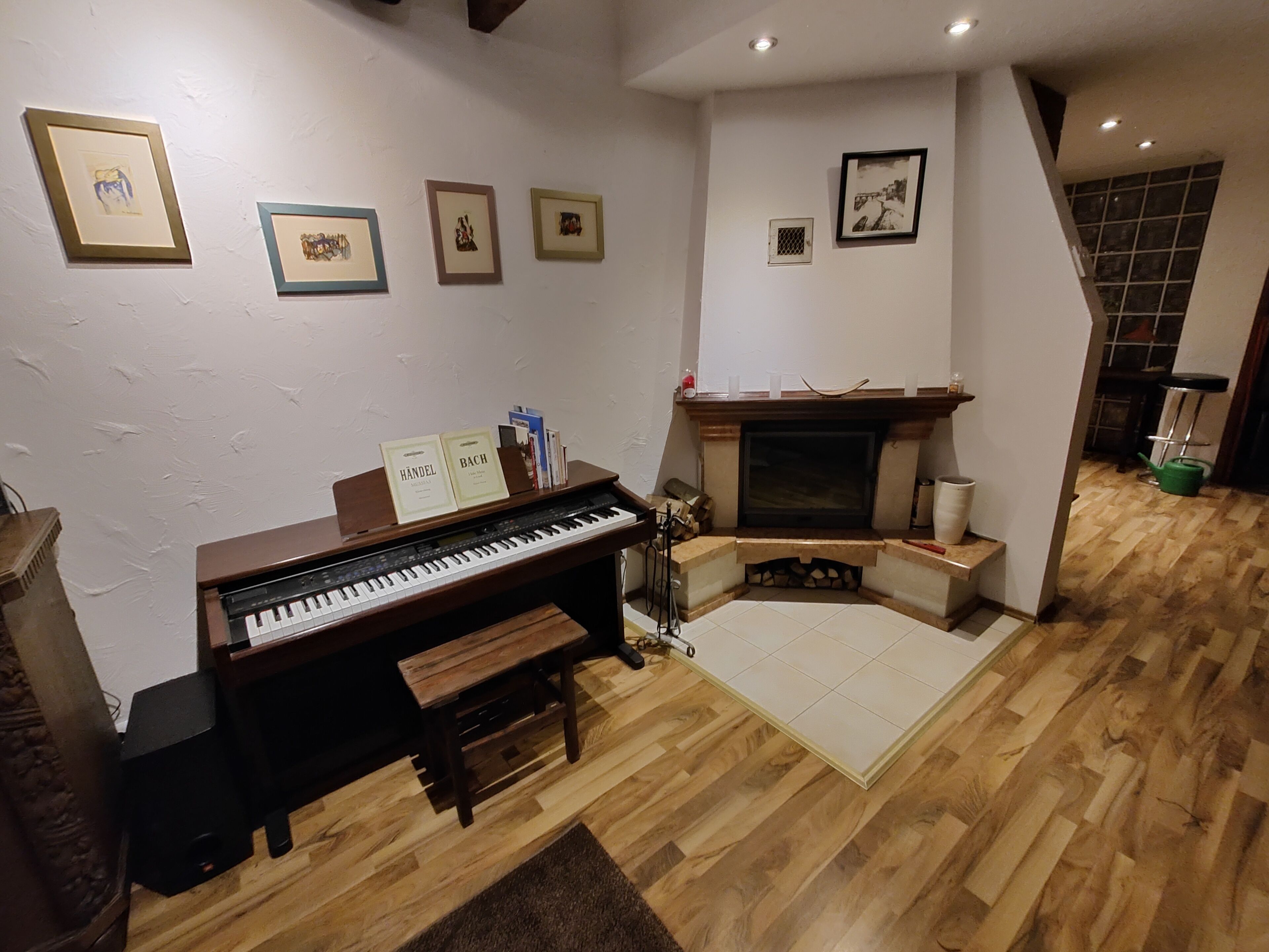 A living room with a piano, fireplace, and framed pictures on the wall.