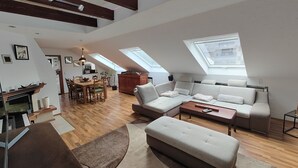 A spacious loft with a high ceiling, wooden beams, a dining area, a sofa set, and skylights. - Vacation apartment Biene (Saarbrücken)