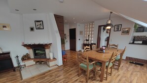 A dining area with a wooden table and chairs, a fireplace, and a staircase leading to another room. - Vacation apartment Biene (Saarbrücken)
