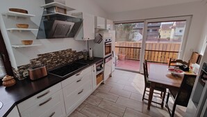 A modern kitchen with white cabinets, a black countertop, and a built-in stove. There is a sliding glass door leading to an outdoor patio. - Vacation apartment Biene (Saarbrücken)