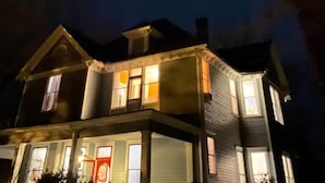 Een huis met twee verdiepingen, een veranda en een rode deur.