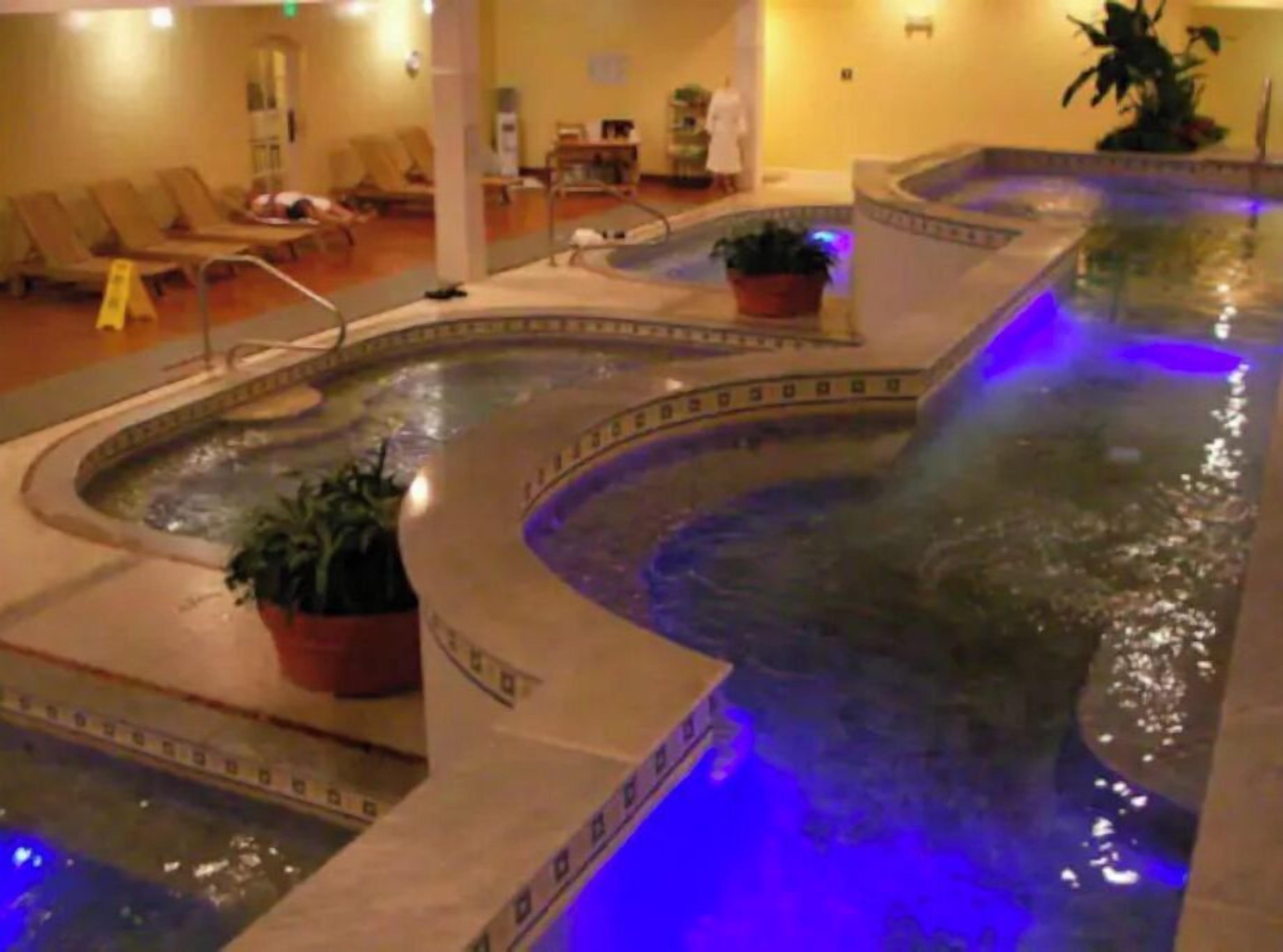 A spa area with a hot tub, lounge chairs, and potted plants.