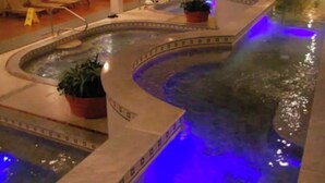 Een wellnessruimte met een bubbelbad, lounge fauteuils en potplanten.