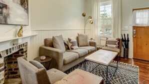 Uma sala de estar acolhedora com lareira, um sofá, uma mesa de centro e um tapete estampado.
