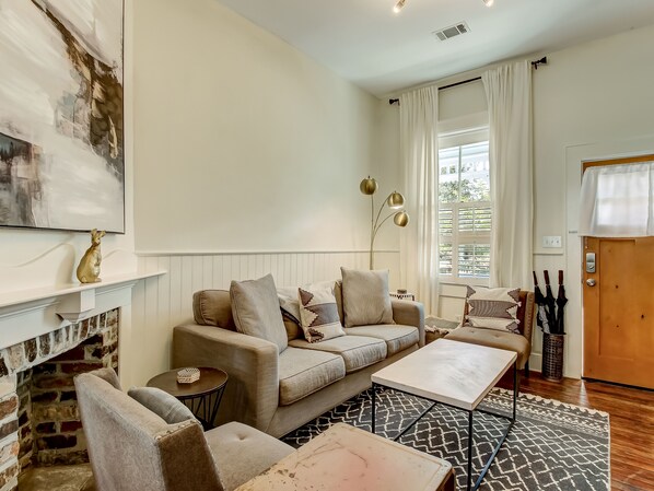 Un salon chaleureux avec une cheminée, un canapé, une table basse et un tapis à motifs.