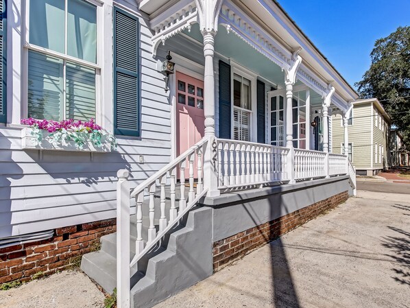 A two-story house with a porch, white railings, and a brick foundation. - Cottage in Historic District, Heated Pool Access (Savannah)