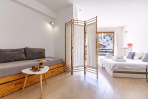 A modern bedroom with a sofa, a bed, a small table, and a view of a snowy landscape.