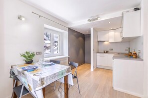 A modern kitchen with white cabinets and a dining area with a table set for two. - Le Bellevue 04 Argentière Village Walk to Lifts & Pool, Argentière (Chamonix), France (Argentière (Chamonix))