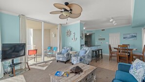 Ein Wohnzimmer mit Fernseher, Deckenventilator und Essbereich mit Stühlen und Tisch.