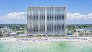 Ein großes Hotel mit mehreren Etagen, direkt am Strand, und einem belebten Strand.
