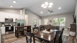 A spacious kitchen with modern appliances, a dining area with wooden furniture, and a ceiling fan. - Cozy House in the Woods - 25 minutes from downtown (Pegram)