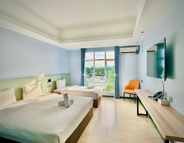 A hotel room with two beds, a desk, a chair, a TV, and a large window with curtains.