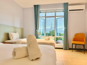 A hotel room with two beds, a view of the outdoors, and an air conditioning unit. - Wing Tat Grand Hotel (Semporna)