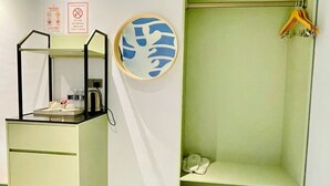 A room with a desk, a mirror, a coat rack, and a wall-mounted artwork. - Wing Tat Grand Hotel (Semporna)
