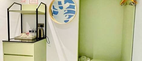 A room with a desk, a mirror, a coat rack, and a wall-mounted artwork.