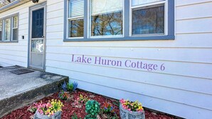 Una cabaña blanca con el nombre 'Lake Huron Cottage 6' en la fachada.