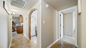 A hallway with a kitchen area, a stone archway, and a closed door. - South Mountain Retreat - Free Heated Pool, Tesla outlet, RV Parking (Phoenix)