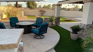 A patio area with a round table and chairs, a pergola with string lights, and a well-maintained lawn. - South Mountain Retreat - Free Heated Pool, Tesla outlet, RV Parking (Phoenix)
