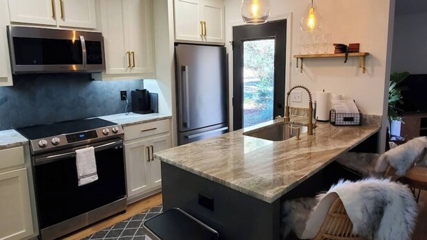 A modern kitchen with white cabinetry, stainless steel appliances, a marble countertop, and pendant lighting. - On Golf Course | Peaceful | Central | Upscale (Columbus)