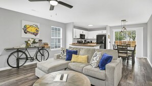 A modern living room with a sofa, coffee table, and a bicycle as a side table. - NEW! Beautiful Updated House w/ Fenced Backyard! (Columbia)