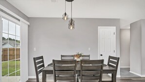 A dining room with a large table, four chairs, and hanging pendant lights. - NEW! Beautiful Updated House w/ Fenced Backyard! (Columbia)