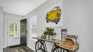A hallway with a wooden bench, a bicycle, a door, and a wall-mounted artwork. - NEW! Beautiful Updated House w/ Fenced Backyard! (Columbia)