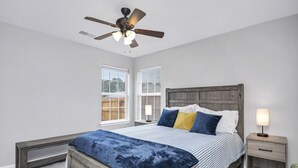 A bedroom with a bed, nightstand, bench, ceiling fan, and windows. - NEW! Beautiful Updated House w/ Fenced Backyard! (Columbia)
