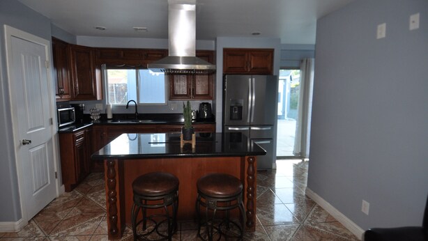 Una cocina con armarios de madera, electrodomésticos de acero inoxidable y una isla central con taburetes.
