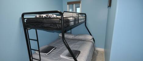 A bunk bed room with a window and a door.